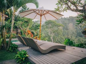 een groep stoelen met een paraplu op een terras bij The Sidemen Villa in Sidemen