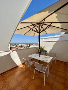 a table with chairs and an umbrella on a balcony at Dos terrazas vistas a la montaña in Vinaròs