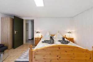 Un dormitorio con una cama de madera con dos gatos. en Ferienwohnungen Lilie Und Dahlie en Münsingen
