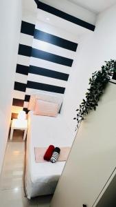 Cama en habitación con pared de rayas en blanco y negro en Brand New Private Partition Near MOE Metro, en Dubái