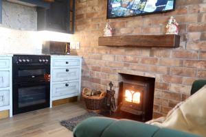 a kitchen with a brick wall with a fireplace at Tara’s Hill Cottage in Kilcoo