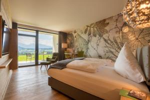 1 dormitorio con cama grande y ventana grande en PANORAMA Allgäu Spa Resort, en Seeg