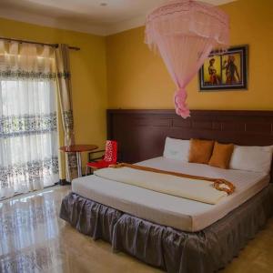 ein Schlafzimmer mit einem großen Bett mit einem rosa Regenschirm darauf in der Unterkunft Kakiri Gardens and Hotel in Wakiso