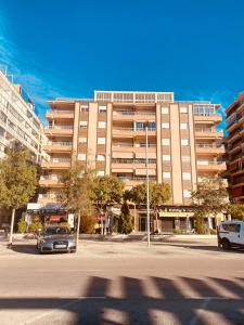 Un gran edificio con coches aparcados en un estacionamiento. en Marina Apartments - Playas, en Santa Pola