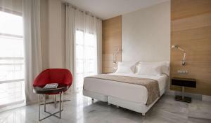 a bedroom with a bed and a red chair at NH Collection Amistad Córdoba in Córdoba