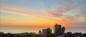 einen Sonnenuntergang über einer Stadt mit Gebäuden und dem Meer in der Unterkunft Plateau Of The Seas in Collaroy