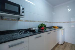 a white kitchen with a sink and a microwave at Apartamentos California in Salou
