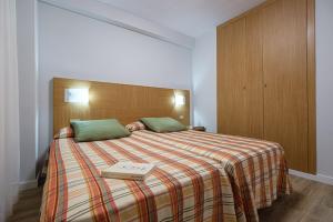 a bedroom with a bed with a book on it at Apartamentos California in Salou