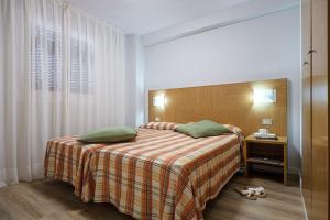 a bedroom with a bed with green pillows on it at Aparthotel California in Salou