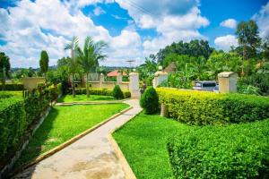 einen Garten mit grünen Hecken und einem Gehweg in der Unterkunft Kakiri Gardens and Hotel in Wakiso