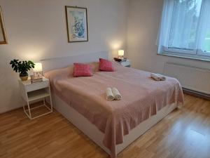 a bedroom with a large bed with pink pillows at Bukor Apartments in Lukovica pri Domžalah