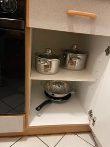 2 casseroles et poêles dans un meuble de cuisine dans l'établissement Appartement Donauwelle 2, à Passau