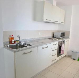 a white kitchen with a sink and a microwave at Tranquil Apartment at Tortuga Beach - 221 in Prainha