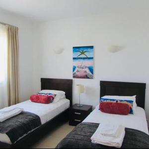una camera d'albergo con due letti con cuscini rossi di Tranquil Apartment at Tortuga Beach - 221 a Prainha