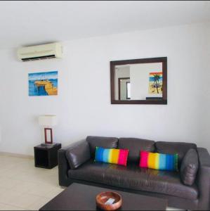 a living room with a brown couch with colorful pillows at Tranquil Apartment at Tortuga Beach - 221 in Prainha