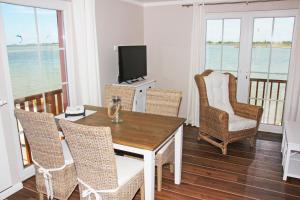 ein Wohnzimmer mit einem Tisch, Stühlen und einem TV in der Unterkunft Meerblick Lemkenhafen in Fehmarn