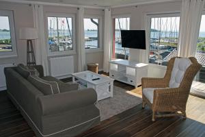 ein Wohnzimmer mit einem Sofa, Stühlen und einem TV in der Unterkunft Meerblick Lemkenhafen in Fehmarn