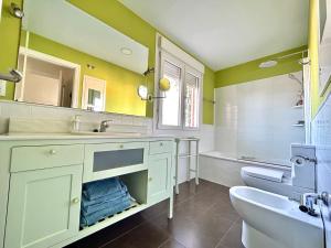uma casa de banho com paredes verdes, um lavatório e um WC. em Hispalis Ático Bermejales em Sevilha