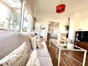 uma sala de estar com um sofá e uma mesa de vidro em Hispalis Ático Bermejales em Sevilha
