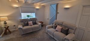 uma sala de estar com duas cadeiras e um sofá em MarMic Cottage em Rothbury