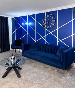 凱特林的住宿－Kettering/Stylish/ Perfect for Contractors，蓝色的长沙发和蓝墙上的钟