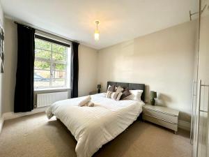 um quarto com uma cama grande e uma janela em Desirable 2 Bedroom Apartment in Bicester that sleeps 5 em Bicester