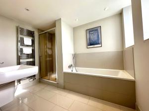 a bathroom with a bath tub and a sink at Desirable 2 Bedroom Apartment in Bicester that sleeps 5 in Bicester