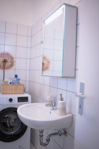 La salle de bains est pourvue d'un lavabo, d'un miroir et d'un lave-linge. dans l'établissement Modernes Apartment in der Altstadt , kostenlose Parkplätze in der Nähe, à Emden