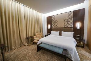 een slaapkamer met een groot wit bed en een stoel bij The Westin Kolkata Rajarhat in Calcutta