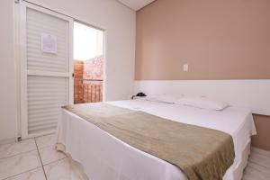 Schlafzimmer mit einem großen weißen Bett und einem Fenster in der Unterkunft Pousada Ma-juli in Olímpia
