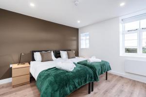 1 dormitorio con 2 camas y mantas verdes en Dovedale Manor, en Tissington