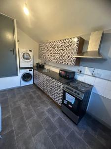 a kitchen with a stove and a washing machine at Samco flat in Ashton in Makerfield