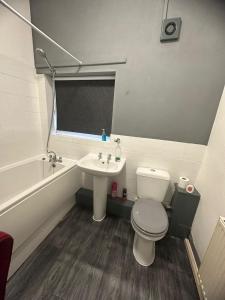 een badkamer met een toilet, een wastafel en een bad bij Samco flat in Ashton-in-Makerfield