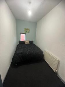 een slaapkamer met een zwart bed in een kamer bij Samco flat in Ashton-in-Makerfield