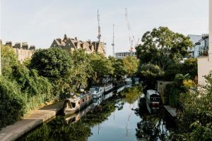 Un río con barcos en él con edificios y árboles en Mason & Fifth, Primrose Hill, en Londres