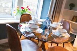 mesa de comedor con sillas y mesa de cristal con copas de vino en Clubhouse Cottage on Eden View Estate, en St Andrews