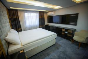 a bedroom with a bed and a tv and a chair at KY Continental Apartments in Izmir