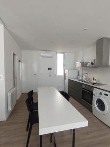 a white kitchen with a white table and appliances at HERMOSO DEPARTAMENTO EN EL CENTRO DE ROSARIO in Rosario +7 photos
