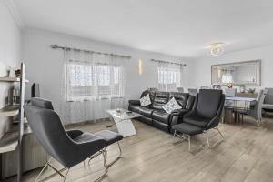 uma sala de estar com um sofá preto e cadeiras em Villa Portugal - Villasexperience em Tahiche