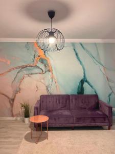 un divano viola in un soggiorno con murale di Premium HILS Pallady a Bucarest