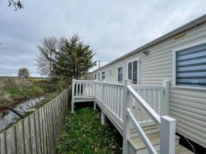 Casa blanca con porche y valla en Wonderful 8 Berth Caravan At Seawick Holiday Park In Clacton-on-sea Ref 27077r, en Clacton-on-Sea