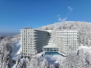 ein Hotel im Schnee vor einem Berg in der Unterkunft Crystal Mountain Hotel Wisła in Wisła