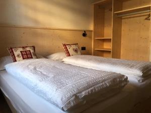 1 dormitorio con 2 camas con sábanas y almohadas blancas en B&B Tilde en Tesero