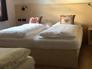 2 camas con sábanas blancas y almohadas en una habitación en B&B Tilde en Tesero