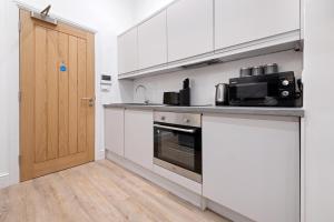 a kitchen with white cabinets and a black oven at The Market Street Studios in Nottingham