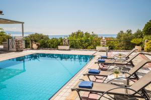 a swimming pool with chaise lounge chairs next to a pool at Villa Petri in Trapezaki