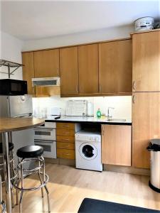 a kitchen with wooden cabinets and a white appliance at Smart 1 Bedroom Apartment in the City - Islington in London