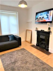 a living room with a black couch and a flat screen tv at Smart 1 Bedroom Apartment in the City - Islington in London