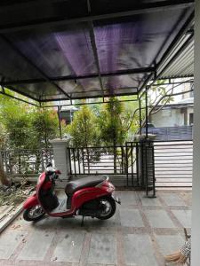 a red scooter parked under a pavilion at Puri Anggrek Homestay in Kerobokan