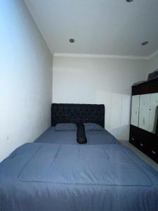 a bedroom with a blue bed with a black headboard at Puri Anggrek Homestay in Kerobokan